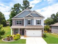 Charming two-story home with stone accents, lush landscaping, and a well-manicured front yard at 3390 Meadow Grass Drive, Dacula, GA 30019