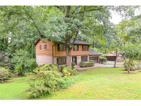 Charming two-story home with brick and wood siding nestled among lush trees, and a sprawling green lawn at 3352 Northbrook Dr, Atlanta, GA 30340