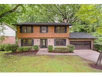 Charming two-story home with wood and brick exterior, lush landscaping, and attached two car garage at 3352 Northbrook Dr, Atlanta, GA 30340