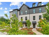 View of a modern white brick townhome with a gray roof and professionally landscaped front yard at 445 Breccia Run, Mcdonough, GA 30253