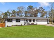 Charming single-story home featuring a manicured lawn, white painted brick, and a welcoming front entrance at 1055 Delmont Ter, Roswell, GA 30075