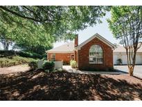 Charming brick home featuring a chimney, front yard landscaping, and beautiful trees at 2191 Rockbridge Rd # 103, Stone Mountain, GA 30087