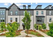 Charming townhome exterior with brick facade, black trim, landscaped yard, and inviting walkways under a partly cloudy sky at 441 Breccia Run, Mcdonough, GA 30253