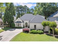 Beautifully landscaped traditional home with painted brick, dark roof, arched entry and circular driveway at 5120 Falcon Chase Ln, Atlanta, GA 30342