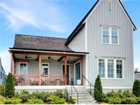 Charming gray two-story home with a welcoming front porch, landscaped yard, and eye-catching blue front door at 11260 Serenbe Ln, Chattahoochee Hills, GA 30268