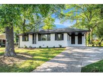 Charming, one-story white brick home featuring a landscaped front yard and mature trees at 1207 Ellington Dr, Morrow, GA 30260