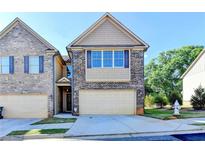 Charming townhome featuring a brick facade, attached garage, and well-maintained landscaping on a sunny day at 4421 Fulson Dr, Lilburn, GA 30047