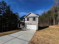 Two-story home with gray siding, brick accents, and a two-car garage on a sunny lot at 192 Paces Lakes Pt, Dallas, GA 30157