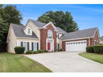 Charming traditional home featuring a red brick facade, manicured lawn, and attached two-car garage at 2525 Highbrooke Trl, Duluth, GA 30097