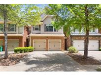 Charming townhome featuring brick accents, a two-car garage, and mature landscaping at 2957 Smith Ridge Trce, Peachtree Corners, GA 30071