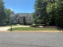 Stately two-story home with a well-manicured front lawn, mature trees, and a circular driveway at 965 Tiverton Ln, Alpharetta, GA 30022