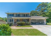 Charming two-story home with brick facade, shutters, landscaped front yard, and a spacious two-car garage at 5166 Vivid Dr, Stone Mountain, GA 30087