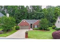Charming red brick home with a well-manicured lawn, mature trees, and an attached two-car garage at 2949 Spotted Pony Nw Ct, Acworth, GA 30101