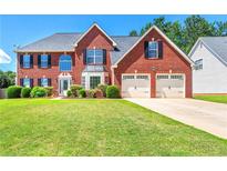 Charming two-story red brick home with a well-manicured lawn and attached two-car garage at 5125 Winding Glen Dr, Lithonia, GA 30038
