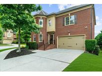 Traditional brick home features a two-car garage, manicured lawn, and mature landscaping at 3086 Frazier Walk, Decatur, GA 30033