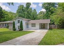 Charming home with a long driveway and a carport, surrounded by lush greenery and a well-manicured lawn at 1585 Melanie Ct, Decatur, GA 30032