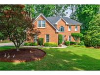 Charming brick home with lush landscaping and a well-manicured lawn at 3620 Chartwell Dr, Suwanee, GA 30024