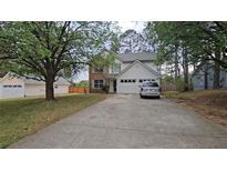 Charming two-story home features a brick facade, vinyl siding, attached two-car garage, and a long concrete driveway at 9693 Pintail Trl, Jonesboro, GA 30238