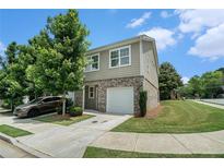 Charming two-story home featuring brick accents, a one-car garage, manicured lawn, and lush green trees at 2039 Wildflower Nw Way, Conyers, GA 30012