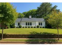 Charming white home with lush green lawn, surrounded by mature trees and a stone retaining wall at 458 Shannon Sw Dr, Atlanta, GA 30310