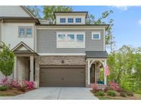 Charming townhome with a brick and gray shingle exterior, complemented by a two-car garage and colorful landscaping at 421 Retreat Ln, Canton, GA 30114