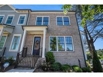 Charming brick townhome featuring a covered front porch, well-maintained landscaping, and a welcoming entrance at 710 Elmwood Way, Roswell, GA 30075