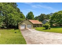 Charming one-story home featuring an attached two-car garage, mature trees, and a well-maintained lawn at 2617 Laurel Woods Se Ln, Conyers, GA 30094