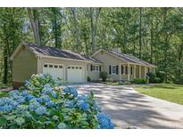 Charming home with attached garage, circular driveway, and landscaped front yard with blue hydrangeas at 4516 Creekwood Circle Nw, Kennesaw, GA 30152