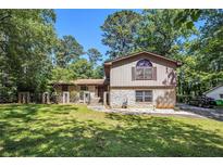 Charming split-level home featuring stone accents, a well-manicured lawn, and mature trees under a clear blue sky at 5491 Valley Brook Road Southeast Se Rd, Mableton, GA 30126