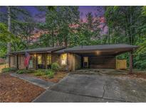 Charming brick home featuring a covered carport, manicured lawn, and patriotic American flag display at 3431 Alcan Way, Tucker, GA 30084