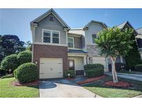 Charming townhome featuring a two-car garage, landscaped yard, and a mix of brick and stone accents at 1071 N Village Dr, Decatur, GA 30032