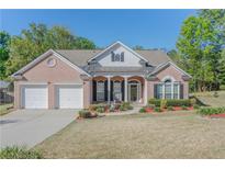 Charming brick home featuring a two-car garage, manicured lawn, and mature trees at 3878 Hannahberry Pl, Buford, GA 30519