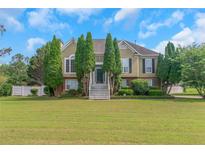 Charming two-story home with a large front yard and mature landscaping, including symmetrical evergreen trees at 147 Midland Dr, Stockbridge, GA 30281