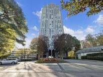 High-rise apartment building featuring manicured landscaping, brick-paved driveway, and tree-lined entrance at 2870 Pharr Court South Nw # 1405, Atlanta, GA 30305