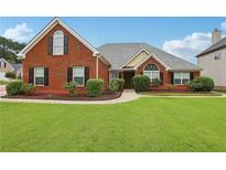 Charming brick home featuring a well-manicured lawn and inviting curb appeal with mature landscaping at 2825 Ellenwood Village Way, Ellenwood, GA 30294