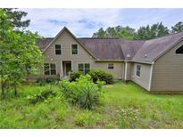 Two-story home featuring classic siding, large windows, and an over-grown yard at 3909 Laurens Ln, Snellville, GA 30039