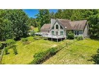 Charming home featuring a large deck, yard and mature trees on a sunny day at 3909 Laurens Ln, Snellville, GA 30039