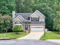 Charming two-story home featuring brick accents, a well-manicured lawn, and a driveway leading to an attached garage at 4000 Mcpherson Drive, Acworth, GA 30101
