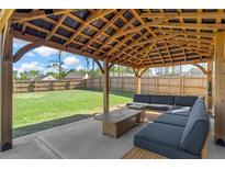 Outdoor seating area features an elegant wood pergola and expansive backyard with lush lawn and privacy fence at 150 Ivy Chase Loop, Dallas, GA 30157