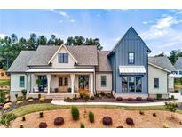 Stunning two-story home featuring a covered porch, meticulous landscaping, and modern farmhouse architectural design at 00 Memory Ln, Canton, GA 30115