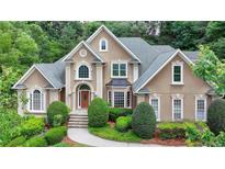 Stately tan home with a gray roof, arched windows, and manicured landscaping offering curb appeal at 5980 Whitestone Ln, Suwanee, GA 30024