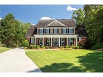 Charming brick home with a columned front porch and well-manicured lawn, offering classic curb appeal at 395 Grove Ridge Dr, Loganville, GA 30052