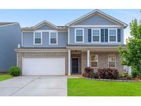 Charming two-story home featuring a brick facade, two-car garage, and beautifully landscaped front yard at 105 Paulowina Cir, Mcdonough, GA 30253