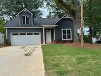 Charming home featuring a well-maintained lawn, and a paved driveway leading to an attached garage at 325 Garrison Se Dr, Marietta, GA 30060