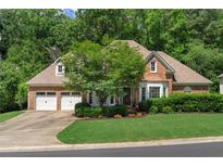 Charming brick home featuring a two-car garage, well-manicured lawn, and lush landscaping at 4381 Laurian Nw Dr, Kennesaw, GA 30144
