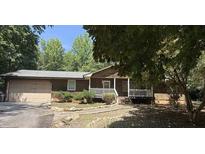 Charming single-story home with a front porch, large trees, and a two car attached garage at 224 Potts Se Rd, Conyers, GA 30094