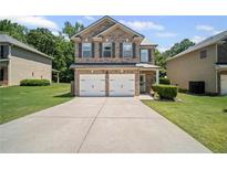 Charming brick two-story home with a well-manicured lawn and a two-car garage at 5575 Hedge Brook Dr, Cumming, GA 30028