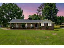 Charming brick home with manicured lawn and lovely curb appeal, complemented by mature trees and an inviting facade at 3642 S Bogan Rd, Buford, GA 30519