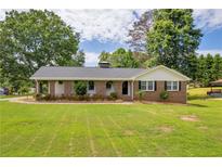 Charming brick home featuring a well-manicured lawn and a welcoming front porch with beautiful trees at 3642 S Bogan Rd, Buford, GA 30519