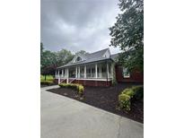 Charming brick home with a welcoming covered front porch, black shutters, and manicured landscaping at 3677 Malachi Way Way, Loganville, GA 30052